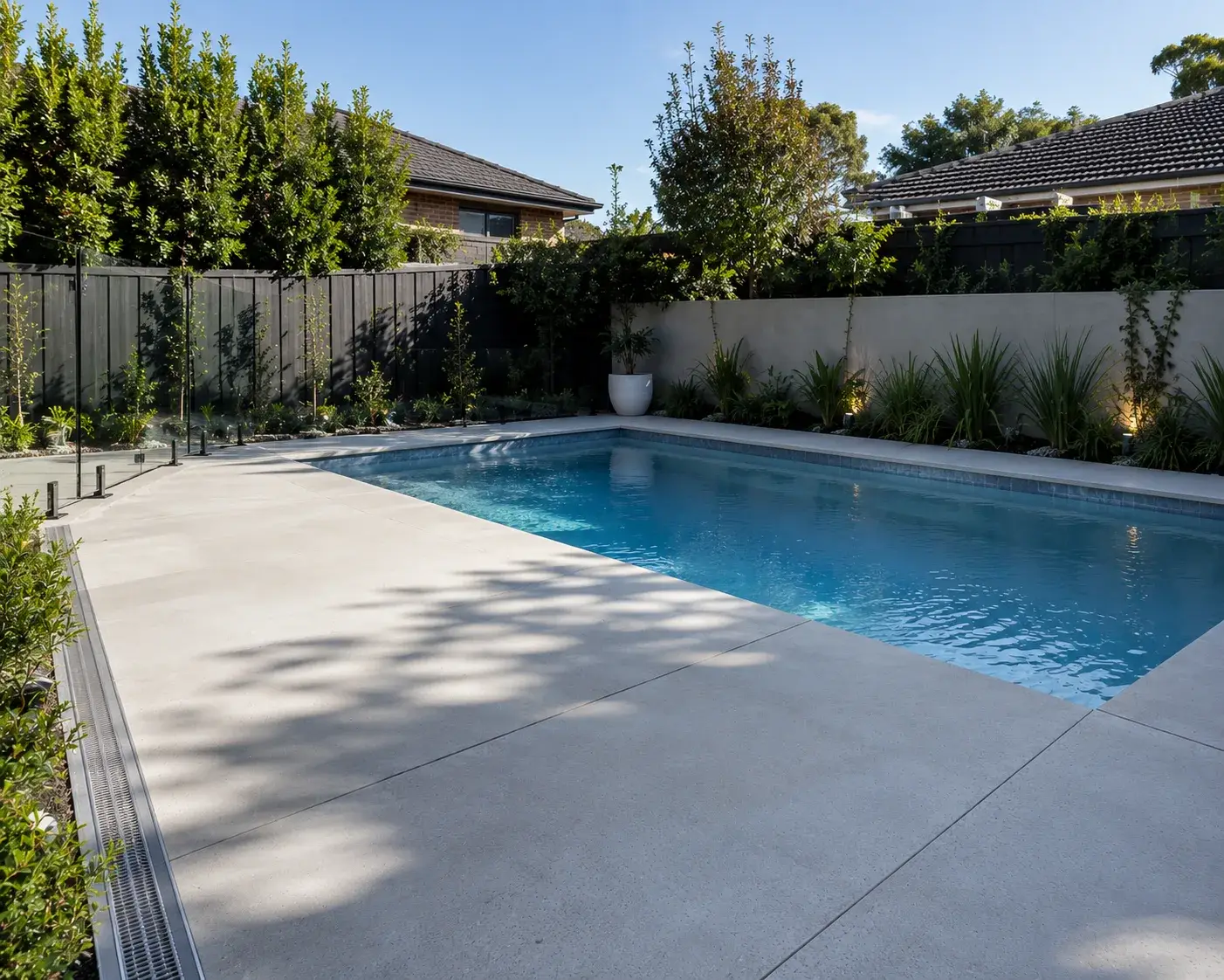 Concrete pool surround beside a backyard pool